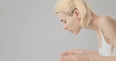 Kadın temiz yüzünü suyla yıkıyor. Genç yetişkin kız yüzünü suyla yıkıyor. Yavaş çekim 4K görüntüsü. Güzellik tedavileri. Cilt bakımı. Sağlıklı cilt kavramı. 