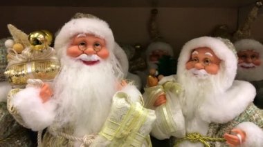 Oyuncak Noel Baba. Noel Baba oyuncakları. Altın elbiseli oyuncak Noel Baba ağacın altında oturuyor. Oyuncak Noel Baba 'yı takip et. 4K video. Noel süsleri. Yeni yıl süslemeleri. 2020 yıl.