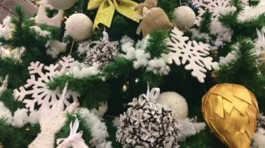 Yılbaşı ağacının yeni yıl süslemeleri. Yılbaşı kürkü ağacındaki Noel oyuncakları süslemeleri. Yeni yıl oyuncakları karla dönüyor. 4K video. Noel süslemeleri.    