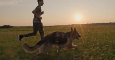 Günbatımında genç bir köpek ile doğada koşuyor. 15 yaşında bir çocuk bir Alman çoban köpeğiyle koşuyor. Sahada köpekli bir genç. Beyaz adam çayırda evcil hayvanıyla oynuyor. Yavaş çekim