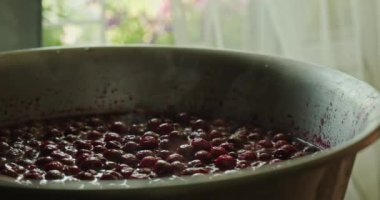 Kiraz reçeli pişiriyorum. Reçel pişirme. Mutfak spatulasıyla leğen kemiğinde kiraz reçeli pişiriyorum. Adam kiraz reçelini karıştırıyor. Ağır çekim. 4k görüntü. 