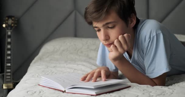 Νεαρός Διαβάζει Βιβλία Στο Σπίτι Ξαπλωμένος Στο Κρεβάτι Ένα Έφηβο — Αρχείο Βίντεο