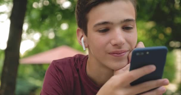 Подросток Использующий Мобильный Телефон Парке Улыбающийся Молодой Человек Использующий Мобильный — стоковое видео
