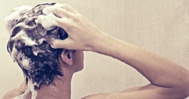 シャワーの中にシャンプーで髪を石鹸若い男のリアビュー ティーンエイジャーはバスルームでシャワーを浴びます 男は暖かい水の流れの下で洗う ヨーロッパの人間は水で髪を育てます スローモーション — ストック動画