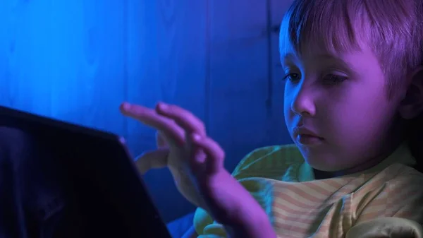 Tabletli 8 yaşında bir çocuk. Küçük çocuk ekrana bakıyor.