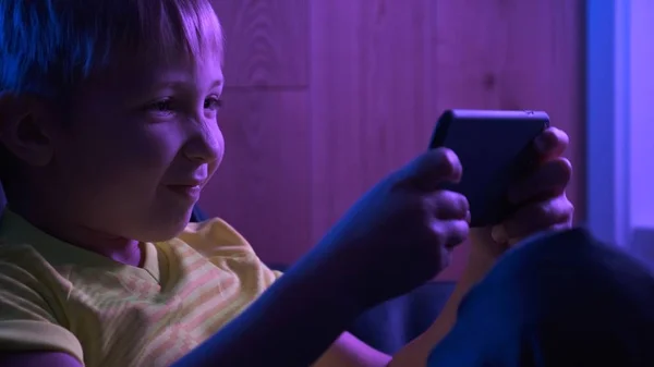 Excited boy plays games, in the evening. Gamer playing in the ga