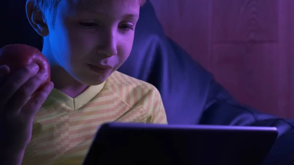 Çocuk ekran tabletine bakar ve elma yer. Tatlı çocuklu.