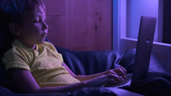 Kind mit Computer zu Hause, 8 Jahre. Junge tippt SMS auf Stockfoto
