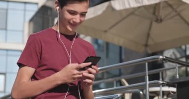 Parkta cep telefonu kullanan bir genç. Açık havada cep telefonu kullanan gülümseyen genç bir adam. Cep telefonu olan mutlu bir çocuk. Şehir manzarası. Yakışıklı adam akıllı telefon kullanıyor. 4 bin. Gerçek zamanlı..