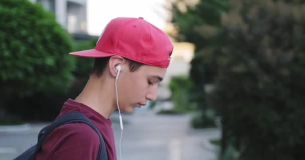 Adolescente Caminando Calle Escuchar Música Los Auriculares Estudiante Con Gorra — Vídeo de stock