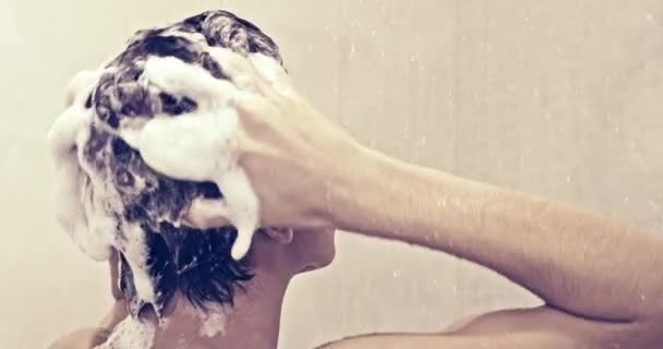 シャワーの中にシャンプーで髪を石鹸若い男のリアビュー ティーンエイジャーはバスルームでシャワーを浴びます 男は暖かい水の流れの下で洗う ヨーロッパの人間は水で髪を育てます スローモーション — ストック動画
