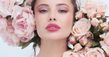 Face with flowers. Beautiful caucasian woman with fresh skin. Closeup female face with flowers. Beauty concept. Skin care. Young girl with natural makeup. 4k. Slow motion