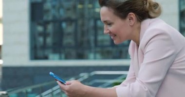 Yetişkin bir kadın kredi kartı ve cep telefonu kullanarak online alışveriş yapıyor. Gülümseyen kadın açık havada, banka kartlı cep telefonuyla online alışveriş yapıyor. Bayan akıllı telefon ve kredi kartı kullanıyor. Gerçek zamanlı.