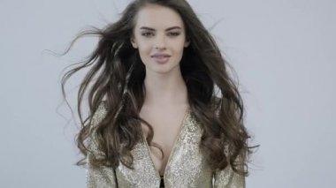 Kıvırcık uzun kahverengi saçlı güzel bir kadının 4K görüntüsü. Moda modeli kameraya bakıyor. Kafkasyalı bir kızın çarpıcı yüzü. Güzel gözleri olan seksi bir manken. Ağır çekim. Güzellik konsepti 