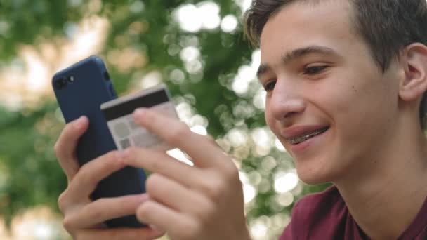 Подросток Делает Онлайн Покупки Помощью Кредитной Карты Мобильного Телефона Улыбающийся — стоковое видео