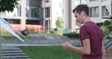 Parkta cep telefonu kullanan bir genç. Açık havada cep telefonu kullanan gülümseyen genç bir adam. Cep telefonu olan mutlu bir çocuk. Şehir manzarası. Yakışıklı adam akıllı telefon kullanıyor. 4 bin. Gerçek zamanlı..