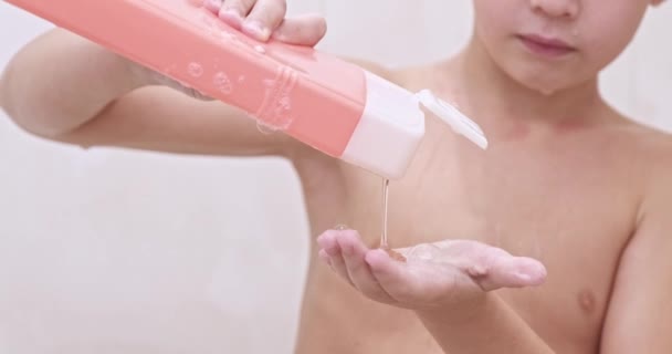 一个小男孩把洗发水塞进了他的手里 拍了个特写镜头 8岁的白人小孩在浴室里洗澡 慢动作 — 图库视频影像