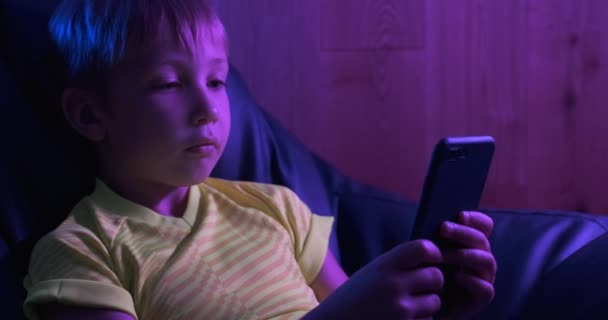 有智能手机的孩子 男孩输入短信 晚上小男孩看着屏幕上的手机 白人小孩拿着电话和打字短信 孩子们在网上消磨时间 — 图库视频影像