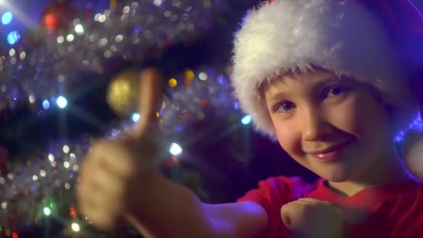 Video Smiling Boy Christmas Tree Shows Thumb Boy Santa Hat — Stock Video