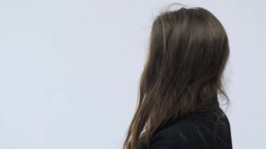 Genç bir kadın dönüp kameraya bakıyor. Stüdyoda poz veren uzun kahverengi saçlı güzel sakin bir kızın portresi. Siyah takım elbiseli güzel esmer bir kadının 4K görüntüsü. Yavaş çekim.  