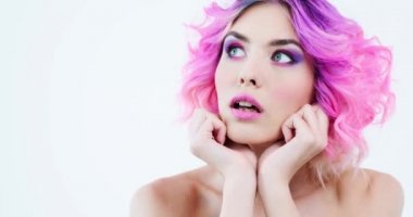  Kız avuçlarına yaslanıyor ve başka tarafa bakıyor. Moda tarzı olan harika bir kadın. Parlak mor saçlı bir mankenin yakın plan portresi. Pembe makyaj. Alışılmadık kişi.