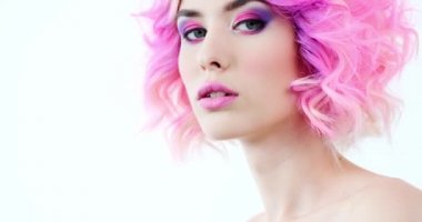 Parlak mor saçlı bir mankenin yakın plan portresi. Moda tarzı olan şık bir kadın. Pembe makyajlı güzel bir yüz. Modaya uygun bir kız. Çekici model kameraya dönüyor. Yavaş çekim