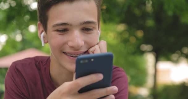 Έφηβος Που Χρησιμοποιεί Κινητό Τηλέφωνο Στο Πάρκο Χαμογελαστός Νεαρός Που — Αρχείο Βίντεο