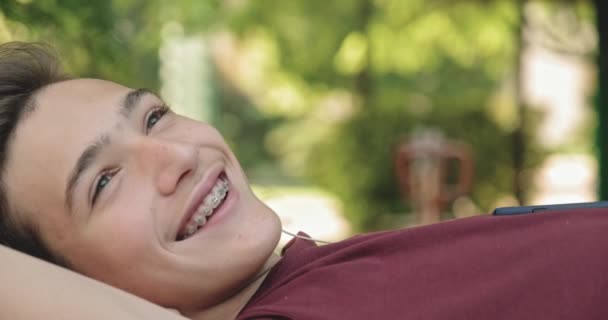 Portret Szczęśliwego Nastolatka Słuchawkach Leżącego Ławce Parku Relaksującego Nastolatek Słucha — Wideo stockowe
