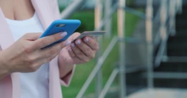 İnsanlar açık havada, kredi kartı ve cep telefonu kullanarak online alım yapıyorlar. Kadın eli cep telefonunu banka kartıyla tutuyor. Kadın eller online alışveriş için akıllı telefon ve kredi kartı kullanır. Yakın çekim..