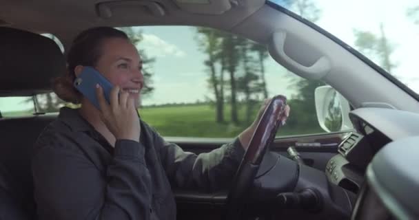 女は車を運転する 車の中で幸せな女性が電話で話している 美しい大人の笑顔の女性が車を運転している 自動車を運転している間に白い大人の女の子が携帯電話で話します リアルタイムだ中へ — ストック動画