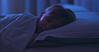 8 yaşındaki çocuk tatlı tatlı beşiğinde uyuyor. Yan yatmış uyuyan bir çocuğun yüzü. Gece yarısı uyuyan bir çocuğun görüntüsü. Rahatla ve dinlen. Yatakta uyuyan bir çocuğun 4K görüntüsü..  