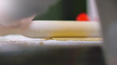 Yavaş çekim 4K - Çocuk hamuru merdaneyle yuvarlıyor, makro. Çocuk hamuru mutfak masasının üzerine atıyor. 8 yaşındaki çocuk evde yemek hazırlıyor. Çocuk elleri merdaneyle hamuru çevirir
