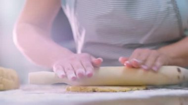 Kadın hamuru mutfak masasına atıyor. Kadın eli merdaneyle hamuru yuvarlıyor, makro. Ev sahibi evde yemek pişiriyor. Kadın eli hamuru yuvarlıyor. Gerçek zamanlı 4k, 60fps