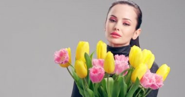 Çiçekli güzel beyaz kız. Sarı lalelerden oluşan büyük buket çiçekleri olan çarpıcı esmer kız. Temiz ciltli, genç ve güzel bir kadının yakından çekilmiş yüzü. Parlak makyajlı kadın. 