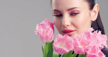 Çiçekli güzel beyaz kız. Pembe lalelerden oluşan büyük buket çiçekleriyle göz kamaştırıcı esmer kız. Temiz ciltli, genç ve güzel bir kadının yakından çekilmiş yüzü. Parlak makyajlı kadın. 