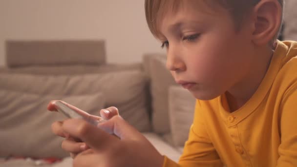 在家里 一个拿着智能手机的男孩的近视 白人儿童用手机在社交网络中度过时光 白人小孩用手机玩游戏生活方式的概念 Hd全片 — 图库视频影像
