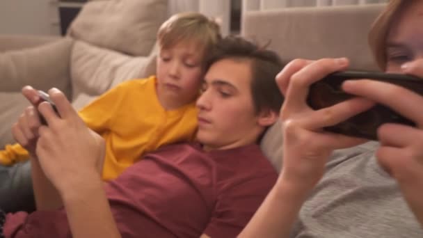 兄弟们在家里用智能手机 两个男孩子用手机在社交网络上消磨时光 孩子们用手机玩游戏 生活方式的概念 完整的Hd实时视频 — 图库视频影像