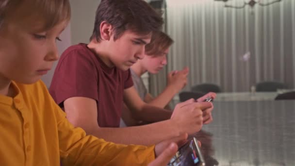 自宅でスマートフォンを持つ10代の男の子 2人の男の子は携帯電話を使ってソーシャルネットワークで時間を過ごしています ゲームに携帯電話を使う白人のティーンエイジャー クローズアップビューを持つ若者 — ストック動画