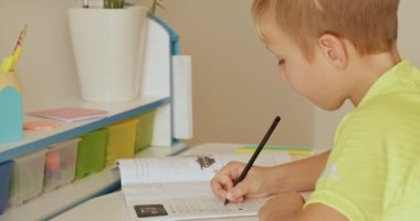 Mektupları okul defterine yazan çocuk. Öğrenci evde el yazısıyla ödev yapıyor. Mektupları okul çocuğu yazıyor. Çocuk okuldan sonra ev ödevi yapar. Gerçek zamanlı. 4k görüntü     