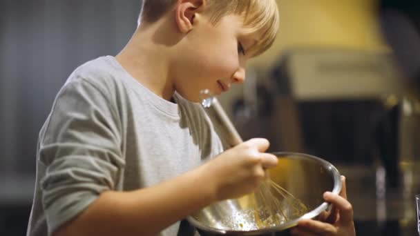 孩子们带着铁皮面罩搅拌蛋黄来做奶油 男孩把面粉混合在一起做饼干 8岁的男孩在厨房里做饭 吃饭时间 童年的概念 — 图库视频影像