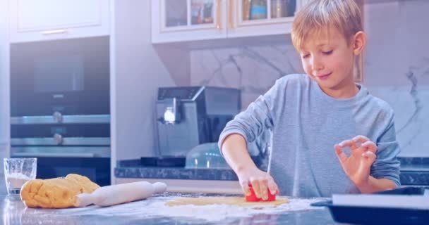 8歳の子供は生地から心を作ります クローズアップビュー 白い子供はクッキーを焼くために生地から心を準備します 台所で 家庭で子供の料理を調理する 4Kスローモーション映像 — ストック動画