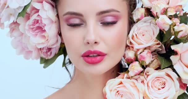 Face with flowers. Beautiful caucasian woman with fresh skin. Closeup female face with flowers. Beauty concept. Skin care. Young girl with natural makeup. 4k. Slow motion
