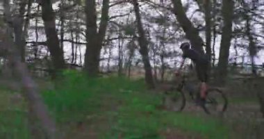 MTB bisikleti süren bisiklet kasklı adamın yan görüntüsü. Orman yolunda çok hızlı giden genç bir bisikletçi. Dağ bisikleti süren bir genç yazın ormanda gezer.. 
