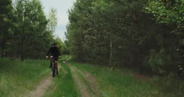 Orman yolunda bisiklet süren genç bir adam. Dağ bisikleti süren bir genç ormanda geziyor. Bisiklet kasklı bir adam MTB bisikleti sürüyor..