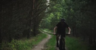 Orman yolunda bisiklet sürerler. Ormanda bisiklete binen bir adam. Bisiklet kasklı yetişkin bir adam yazın MTB bisikletine biner..