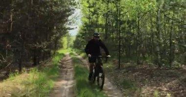 Orman yolunda bisiklet sürerler. Ormanda bisiklete binen bir adam. Bisiklet kasklı yetişkin bir adam yazın MTB bisikletine biner..