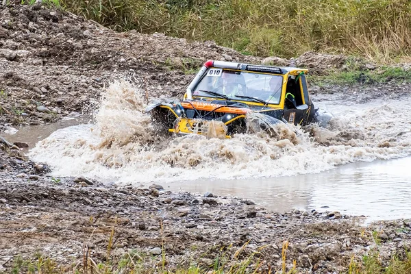 O mașină sport pentru raiduri de raliu și trofee depășește o barieră de apă la viteză mare . — Fotografie, imagine de stoc