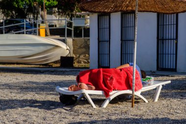 Kumsalda uyuyan evsiz bir adam..