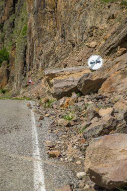 Bir dağ yolundaki yol tabelası kayalıklarla dolu, dikey..