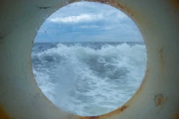 Tormenta en el mar a través del ojo de buey cubierto de hielo de la nave, la corrosión en las partes metálicas es visible . —  Fotos de Stock